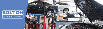 vehicles on lifts in the back of an auto repair shop