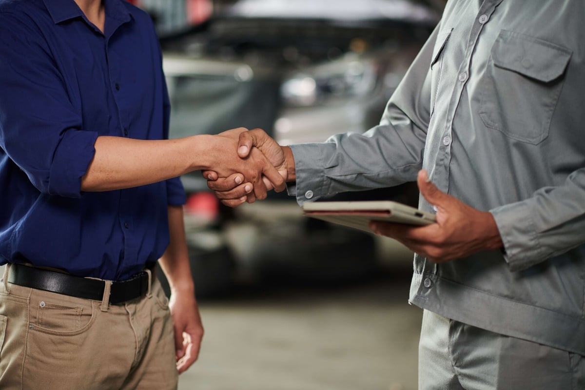 client and small shop owner shaking hands over digital vehicle inspection service 